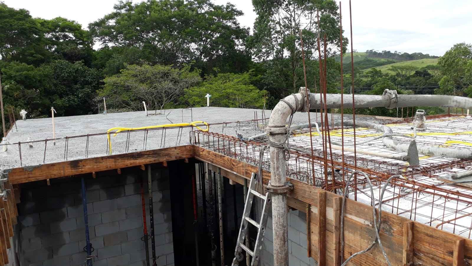 Concretagem de laje em obra residencial com equipe técnica, caminhão betoneira e estrutura preparada