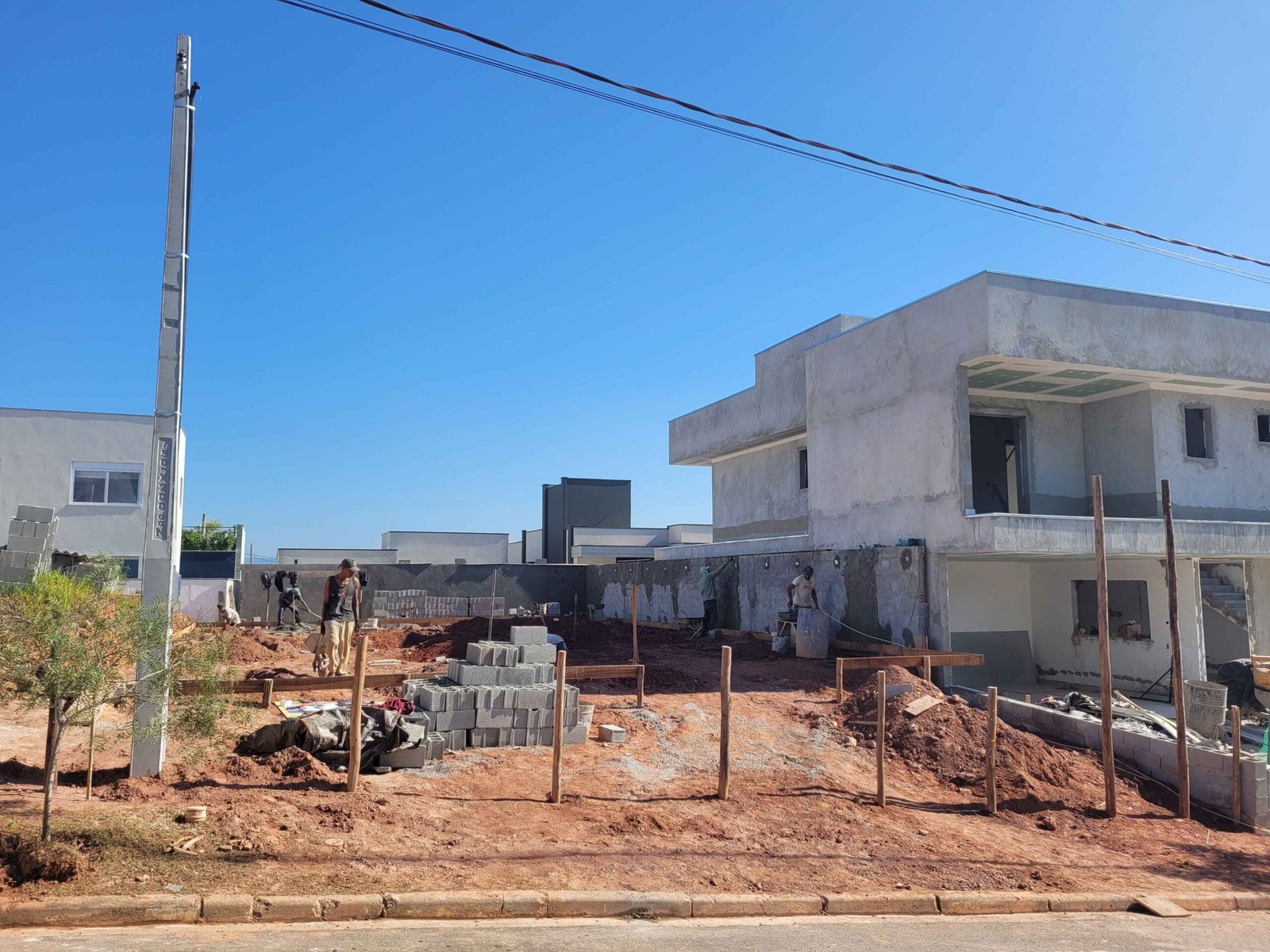 Fachada de casa de alto padrão em construção com equipe executando serviços na área externa