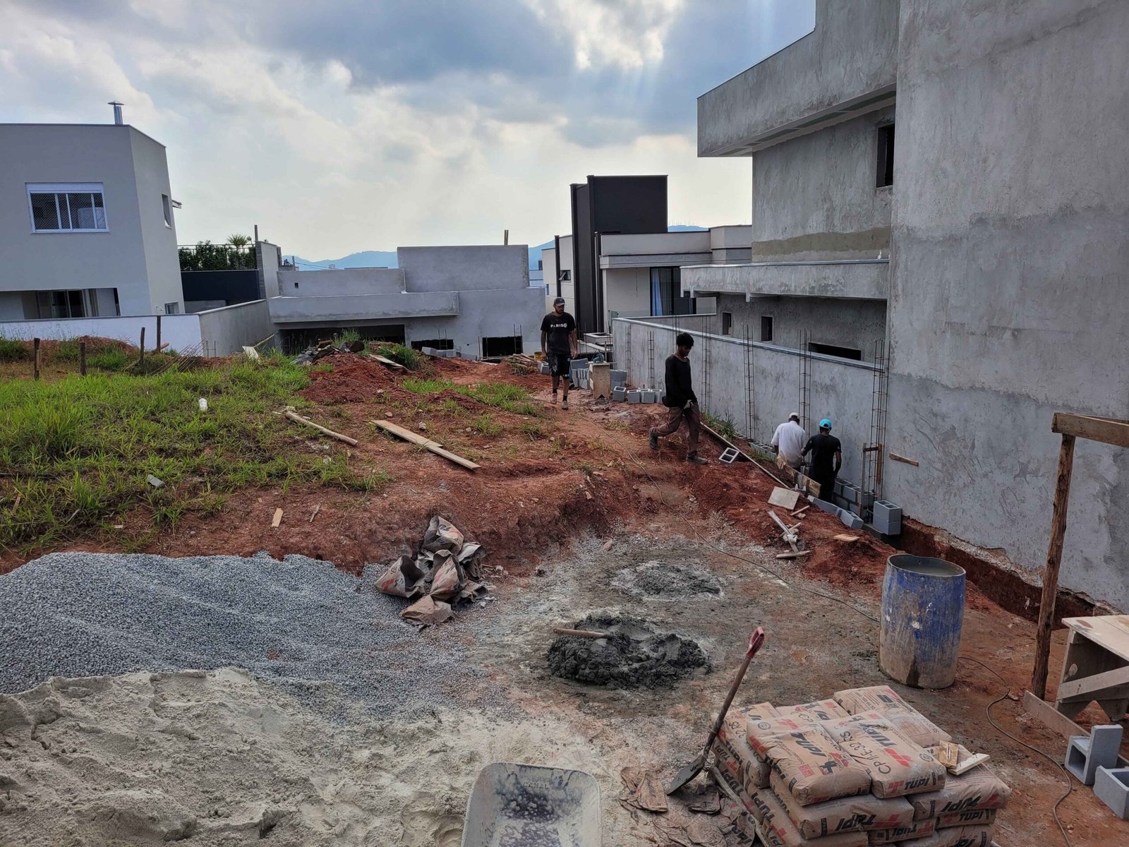 Terreno de casa de alto padrão em fase de preparação com equipe trabalhando na área externa da obra
